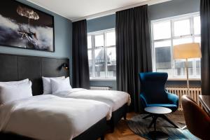 a hotel room with two beds and a blue chair at Radisson Blu 1919 Hotel, Reykjavík in Reykjavík