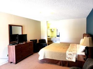 um quarto com uma cama e uma televisão numa cómoda em Motel 103 em Calhoun