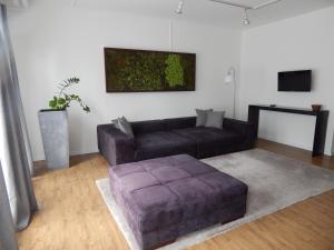 ein Wohnzimmer mit Sofa und Ottomane in der Unterkunft FREE Apartment - Am Kurpark in Bad Urach