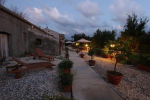a patio with benches and potted plants in a garden at Turismo Rurale Al Benefizio in Monforte San Giorgio Marina