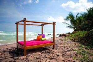 ein Holzbett am Strand mit dem Meer in der Unterkunft UTMT - Underneath The Mango Tree Spa & Beach Resort in Dikwella