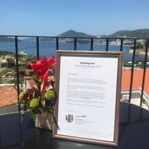 ein Schild auf dem Tisch mit Blumen auf dem Balkon in der Unterkunft Apartments Villa Luka in Sveti Stefan