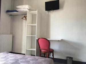 een kamer met een rode stoel en een boekenplank bij Hôtel Océan in Lourdes