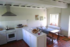 een keuken met witte kasten en een tafel met een wastafel bij Holiday Home Bonjour Clara in Alveringem
