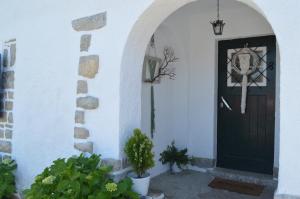 une porte noire dans un bâtiment blanc avec des plantes dans l'établissement Casalinho De Santo António, à Sintra