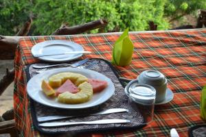 a plate of food on a table with a plate of fruit at Hornbill Bush Lodge in Pakwach East +23 photos