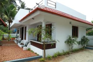 een wit huis met een rood dak bij Alleppey - The Beach Home in Alleppey