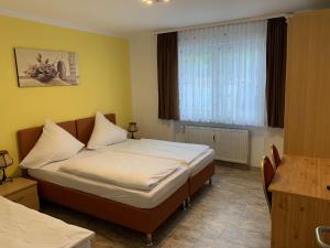 a bedroom with a bed with white sheets and a window at Schnitzelhaus und Pension Stadt Rosbach in Rosbach vor der Höhe +47 photos