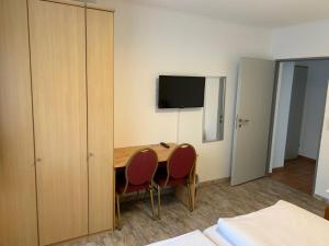 a room with a table and two chairs and a television at Schnitzelhaus und Pension Stadt Rosbach in Rosbach vor der Höhe