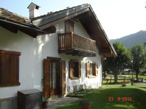 Casa blanca con puertas de madera y balcón en Mansarda - La Thuile Frazione Buic, en La Thuile