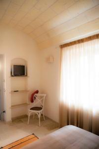 a bedroom with a bed and a tv and a chair at Villa Vittoria in Cisternino