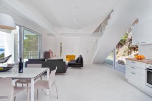 una cucina bianca e un soggiorno con tavolo e sedie di Villa V - private pool, special location & surroundings a Mimice