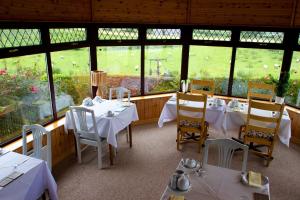 um restaurante com mesas e cadeiras brancas e janelas em Mourneview B & B em Carlingford