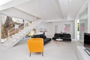 un soggiorno con divano nero e sedia gialla di Villa V - private pool, special location & surroundings a Mimice Altre 40 foto