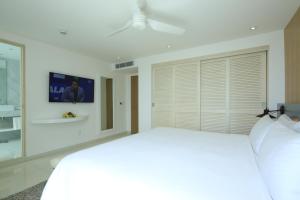 
a room with a bed and a television at Oleo Cancun Playa Boutique All Inclusive Resort in Cancún
