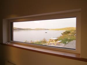 a window in a room with a table and a lake at Otter Bunkhouse in Cairisiadar