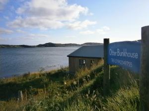 a sign in front of a building next to a body of water at Otter Bunkhouse in Cairisiadar