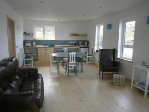 ein Wohnzimmer mit einem Tisch und Stühlen sowie eine Küche in der Unterkunft Otter Bunkhouse in Cairisiadar