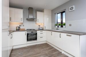 a white kitchen with white cabinets and a window at The Huntington - Donnini Apartments in Ayr