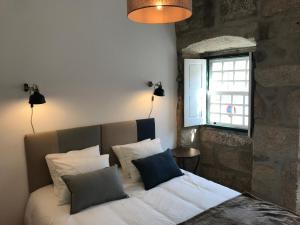 a bedroom with a bed with pillows and a window at Casa da Muralha Cerveira in Vila Nova de Cerveira