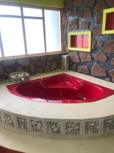 a red tub in a bathroom with a stone wall at Rancho los Alebrijes Zacatlan in Zacatlán