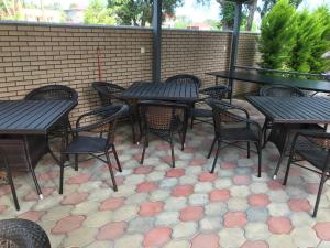 un patio avec des tables et des chaises et un mur en briques dans l'établissement Guest house BAGRATIONI, à Kobuleti