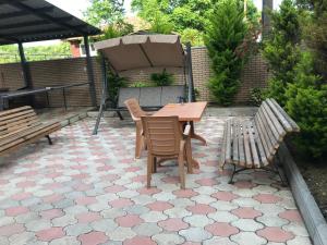 une table et des chaises sur une terrasse avec deux bancs dans l'établissement Guest house BAGRATIONI, à Kobuleti