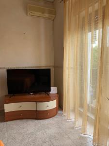 een woonkamer met een flatscreen-tv naast een raam bij Playa Apartment in Catania