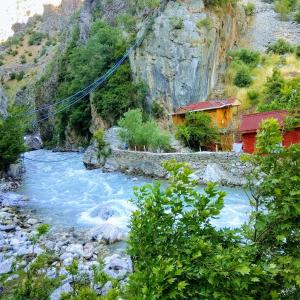 Kapuzbaşı Şelalesi Baştürk dinlenme tesisleri في بويوكتشاكير: نهر فيه منزل على جانب جبل