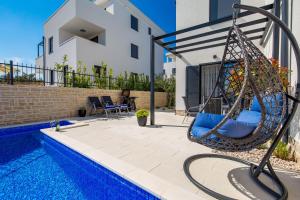 a swing by a swimming pool next to a house at Luxury Apartment Joo & Joo in Murter