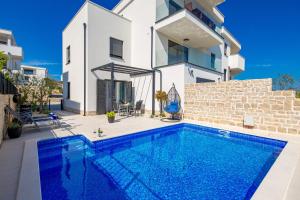 a swimming pool in front of a house at Luxury Apartment Joo & Joo in Murter