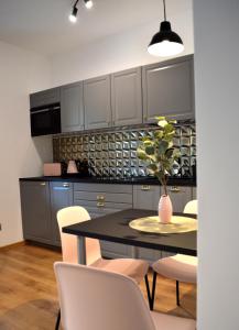 a kitchen with a black table and white chairs at Apartament przy Parku in Polanica-Zdrój