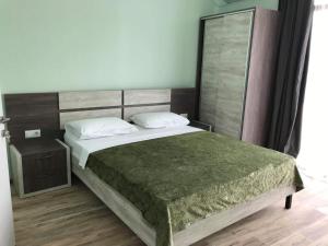 Hotel Royal Georgia في باتومي: غرفة نوم بسرير كبير مع بطانية خضراء