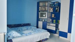 a blue room with a bed and a tv at Gabriella vendégház in Lăzarea