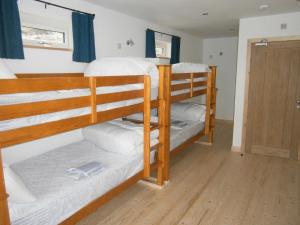 Zimmer mit 2 Etagenbetten und einer Tür in der Unterkunft Otter Bunkhouse in Cairisiadar