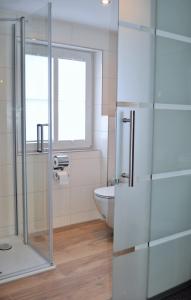 a bathroom with a toilet and a glass shower at Hotel Restaurant Große Teichsmühle in Dülmen +37 photos