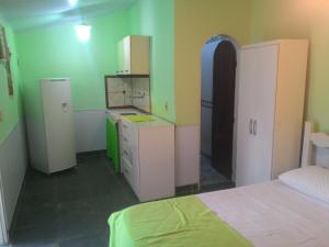 una cocina con armarios blancos y una cama en una habitación en Guest House Giulio Cesare, en Búzios