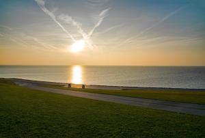 a sunset over the ocean with the sun in the sky at Hus Möwenschiet in Büsum