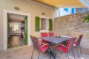 a patio with a table and chairs and a stone wall at At home in Osor, Cres in Osor