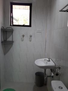 a white bathroom with a sink and a window at Gal's Guesthouse in Siquijor