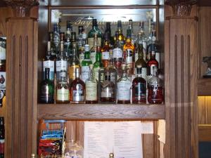 a wooden shelf filled with bottles of alcohol at Tayside Hotel in Stanley