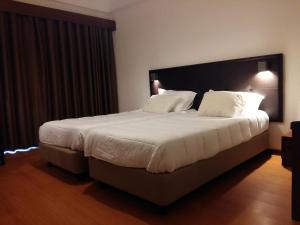 een slaapkamer met een groot bed met witte lakens en kussens bij Riabela Inn in Torreira