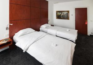 2 bedden in een hotelkamer met witte lakens bij Hotel de Bordeaux in Pons