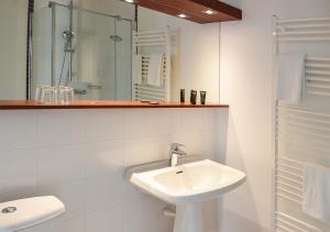 een witte badkamer met een wastafel en een douche bij Hotel de Bordeaux in Pons