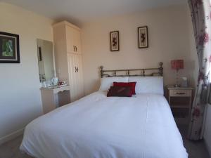 a bedroom with a white bed with a red pillow at Edenvale Bed & Breakfast in Portnoo