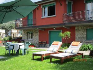 un patio con mesa, sillas y sombrilla en Villa Leilani B&B en Sale Marasino