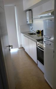 Il comprend une cuisine blanche équipée d'une cuisinière et d'un réfrigérateur. dans l'établissement 2 Confortable departamento con cochera para 2 a 4 pax, à Bahía Blanca