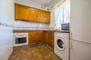 a kitchen with wooden cabinets and a washer and dryer at Chalet Miriam II in Conil de la Frontera