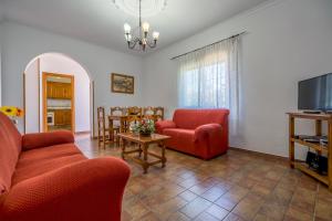 uma sala de estar com duas cadeiras vermelhas e uma televisão em Chalet Miriam II em Conil de la Frontera