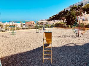 a playground with a ladder and a swing set at Apartamento Rincón, Ideal para familias in Cala del Moral